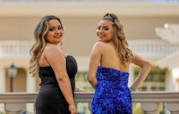 two women in black dresses standing on a balcony