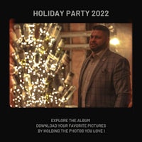 a man in a suit standing in front of a christmas tree