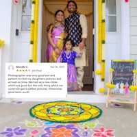 a family is standing in front of a door with a rangoli